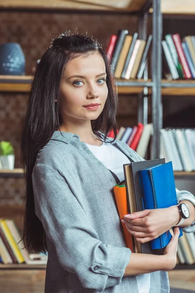 Girl with books in library — Stock Photo