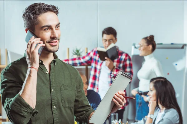 Man with clipboard talking on smartphone — Stock Photo