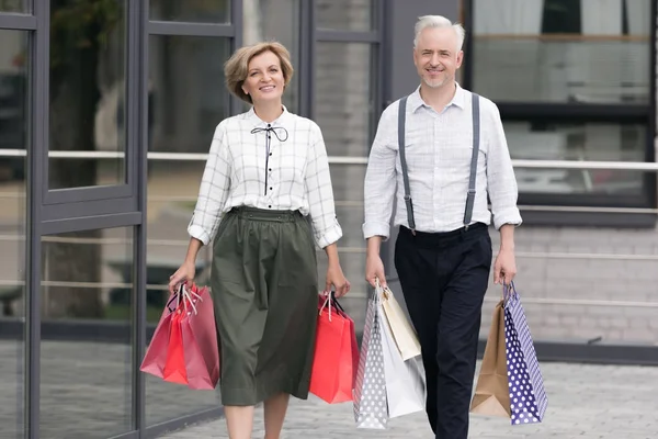 Marido e esposa andando com sacos de compras — Fotografia de Stock