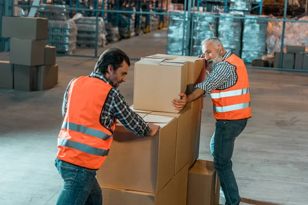 Рабочие склада перевозят коробки — стоковое фото