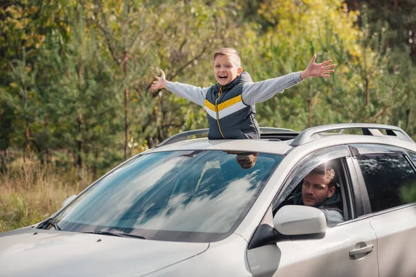 Boy standing in car sunroof — Stock Photo