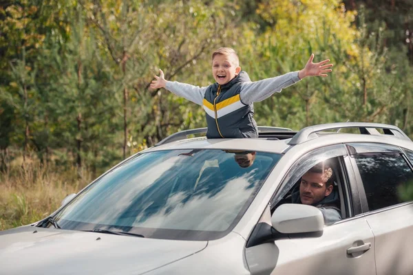 Menino de pé no teto do carro — Fotografia de Stock