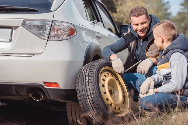 Père et fils changeant de roue de voiture — Photo de stock