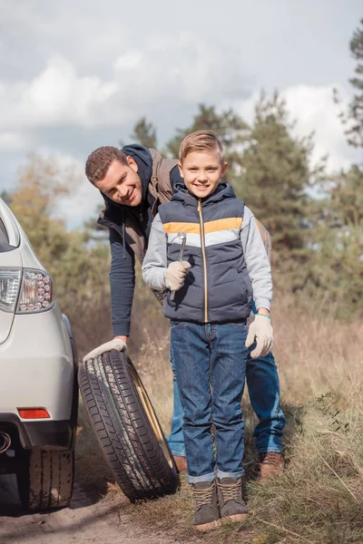 Padre e hijo cambiando la rueda del coche - foto de stock