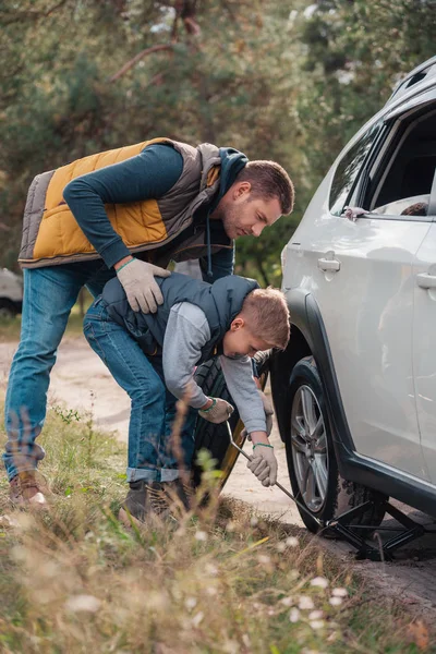 Padre e hijo cambiando la rueda del coche - foto de stock