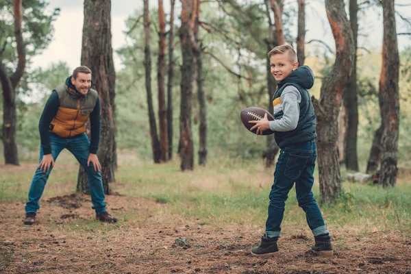 Pai e filho brincando com bola na floresta — Fotografia de Stock