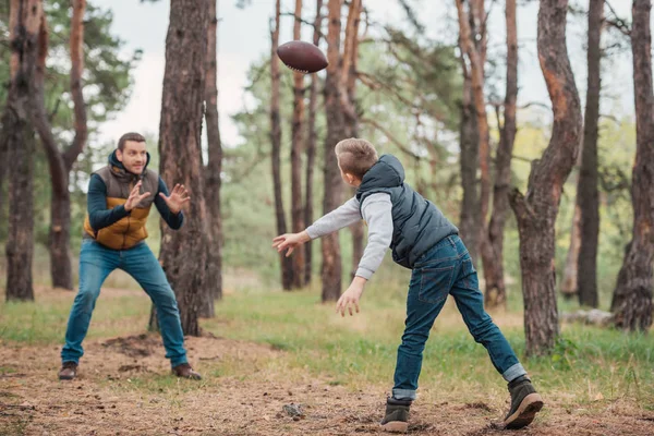 Padre e hijo jugando con pelota en el bosque - foto de stock