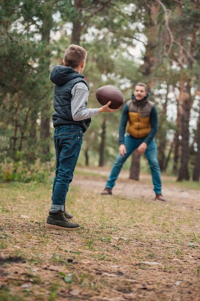 Pai e filho brincando com bola na floresta — Fotografia de Stock