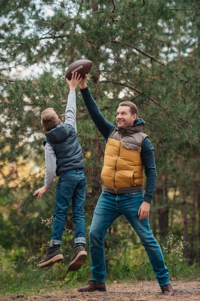 Pai e filho brincando com bola na floresta — Fotografia de Stock