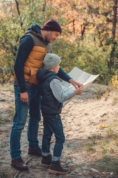 Padre e hijo con mapa en el bosque - foto de stock