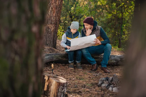 Padre e hijo con mapa en el bosque - foto de stock