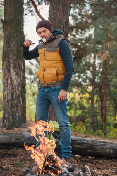 Homem comendo marshmallow na floresta — Fotografia de Stock