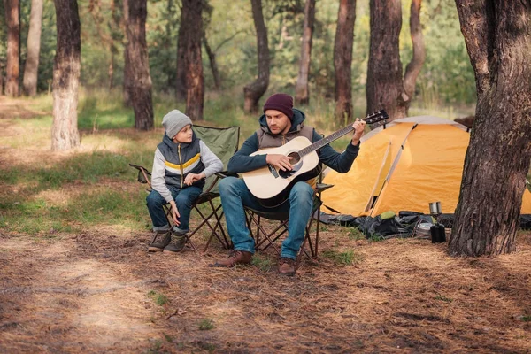 Padre e hijo con guitarra en el bosque - foto de stock