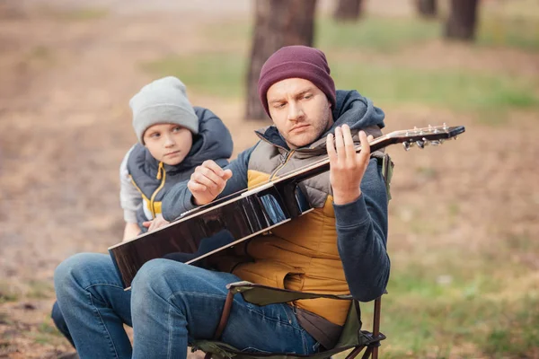 Padre e hijo con guitarra en el bosque - foto de stock