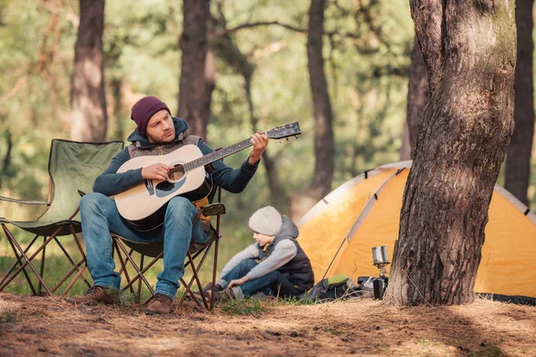 Padre e hijo con guitarra en el bosque - foto de stock