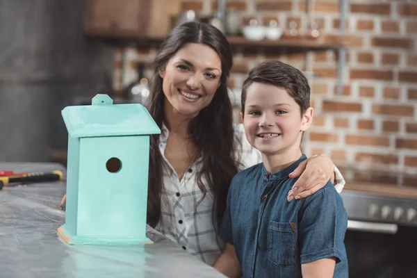 Hijo y madre con pajarera de madera - foto de stock