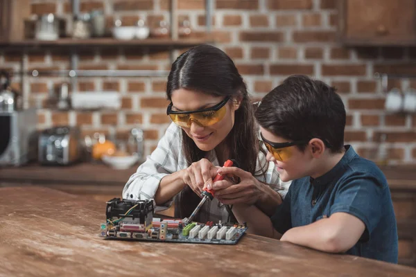 Mother and son soldering mothernoard — Stock Photo