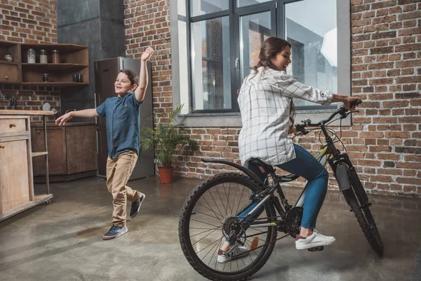 Mujer montar en bicicleta en casa - foto de stock