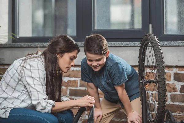 Mother examining deflated bicycle tire — Stock Photo