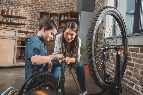 Madre e hijo fijando neumático de bicicleta - foto de stock
