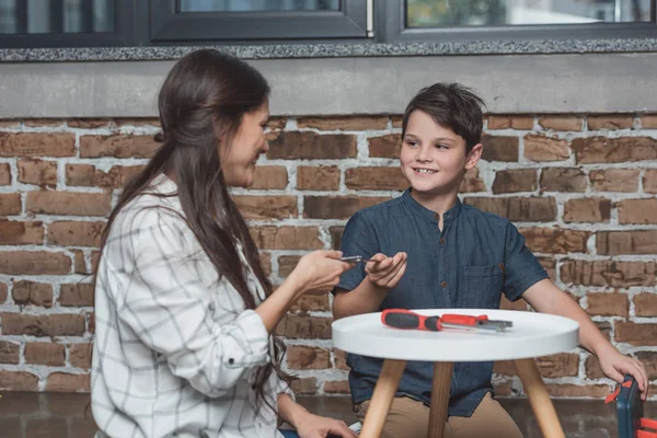 Woman giving pliers to son — Stock Photo