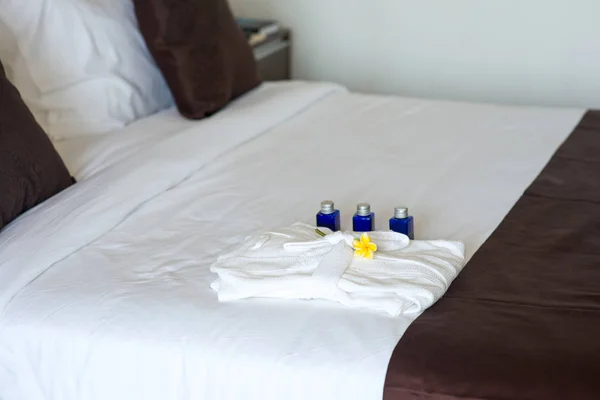 Bathroom amenities with bathrobe on bed — Stock Photo