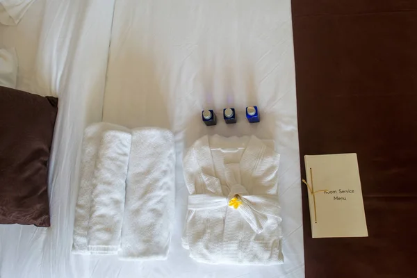Asciugamani arrotolati e accappatoio sul letto — Foto stock
