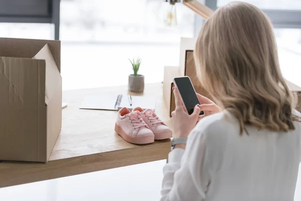 Teilbild einer Geschäftsfrau, die im Büro ein Produkt auf dem Smartphone fotografiert — Stockfoto