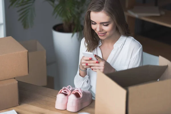 Усміхнена бізнес-леді фотографує продукт на смартфоні в офісі — стокове фото