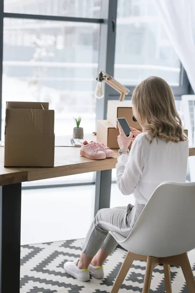 Teilbild einer Geschäftsfrau, die im Büro ein Produkt auf dem Smartphone fotografiert — Stockfoto