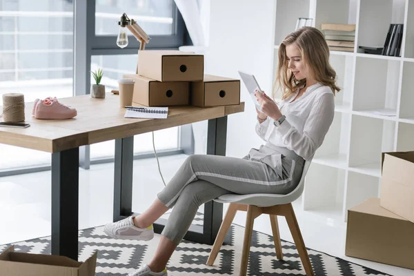 Вид сбоку на молодую предпринимательницу, сидящую за столом с цифровым планшетом — стоковое фото