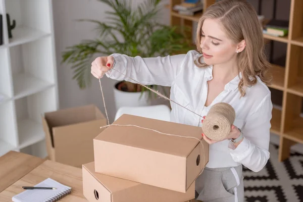 Entrepreneur packing customers purchase in cardboard boxes at home office — Stock Photo