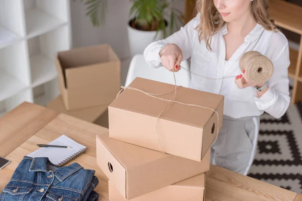 Partial view of entrepreneur packing customers purchase in cardboard boxes at home office — Stock Photo