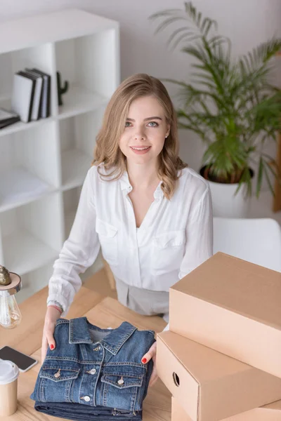 Hochwinkelaufnahme eines jungen Unternehmers, der beim Einpacken im Home Office auf die Kamera schaut — Stockfoto