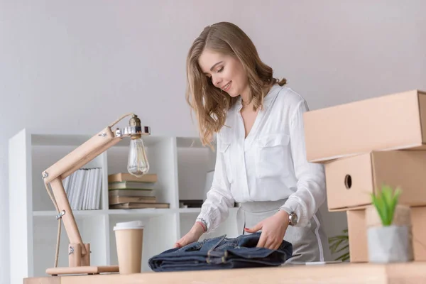 Young smiling entrepreneur packing customers purchase at home office — Stock Photo