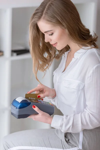 Visão lateral do jovem empreendedor fazendo pagamento com leitor de cartão de crédito no escritório em casa — Fotografia de Stock