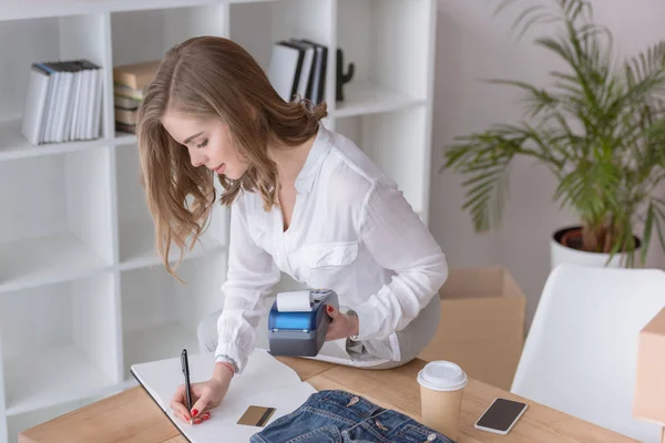 Боковой вид молодого предпринимателя с считывателем кредитных карт, работающего в домашнем офисе — стоковое фото