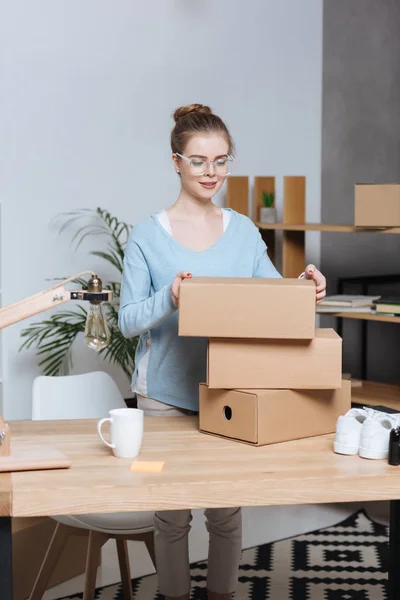Предприниматель с картонными коробками работает в домашнем офисе — стоковое фото