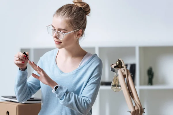 Portrait de jeune femme appliquant vernis à ongles à la maison — Photo de stock