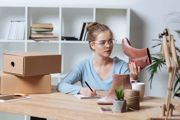 Retrato de empreendedor focado com par de sapatos e notebook trabalhando à mesa no escritório em casa — Fotografia de Stock