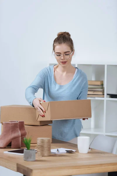 Online shop proprietor with cardboard boxes working at home office — Stock Photo