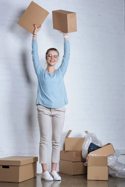 Cheerful entrepreneur holding cardboard boxes and looking at camera at home — Stock Photo