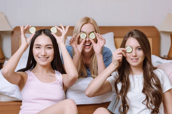 Trois belles filles multiethniques couvrant les yeux avec des morceaux de concombre — Photo de stock