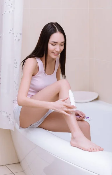 Sorrindo asiático menina barbear perna no banheiro — Fotografia de Stock