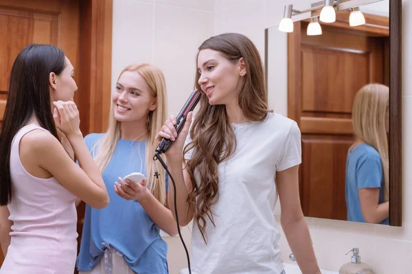 Chica cantando en baño con plancha de pelo - foto de stock