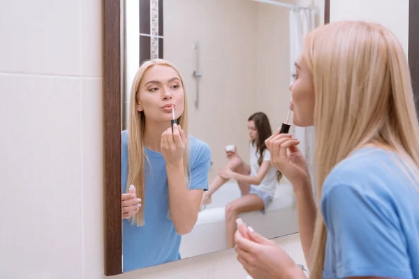 Attraente ragazza applicando labbra lucentezza in bagno — Foto stock