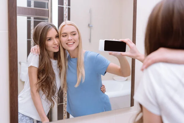 Friends taking selfie with smartphone in bathroom — Stock Photo