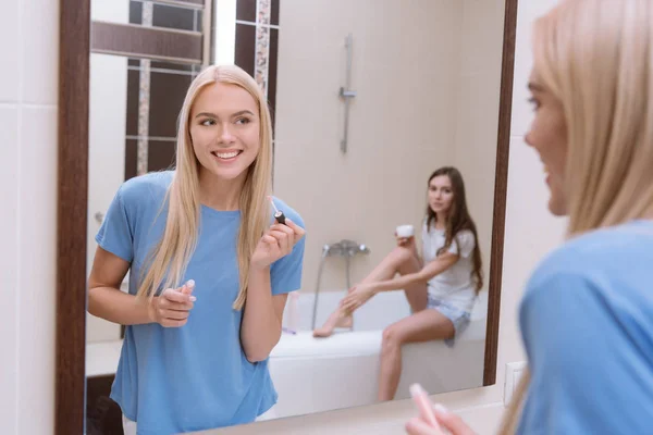 Chica sonriente de pie con los labios brillo en el baño - foto de stock