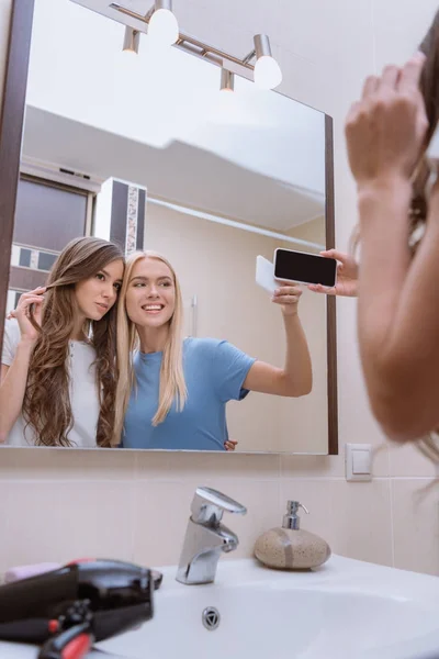 Friends taking selfie with smartphone in bathroom — Stock Photo