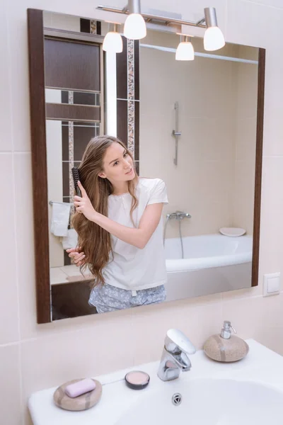 Приваблива дівчина розчісує волосся у ванній вранці — стокове фото